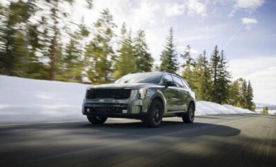 A sleek black SUV driving on a snowy forest road.