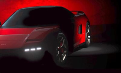 Sleek red sports car illuminated against a dark background.