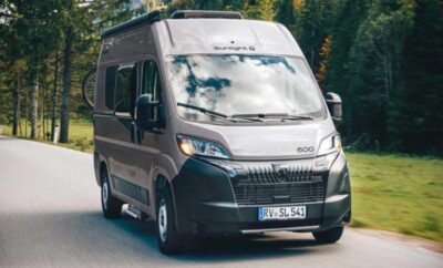 Modern camper van driving on a forest road.
