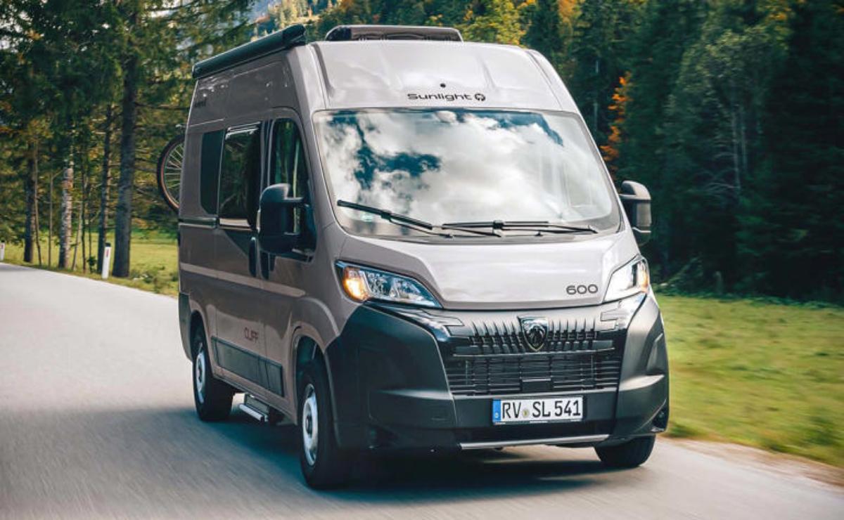 Modern camper van driving on a forest road.