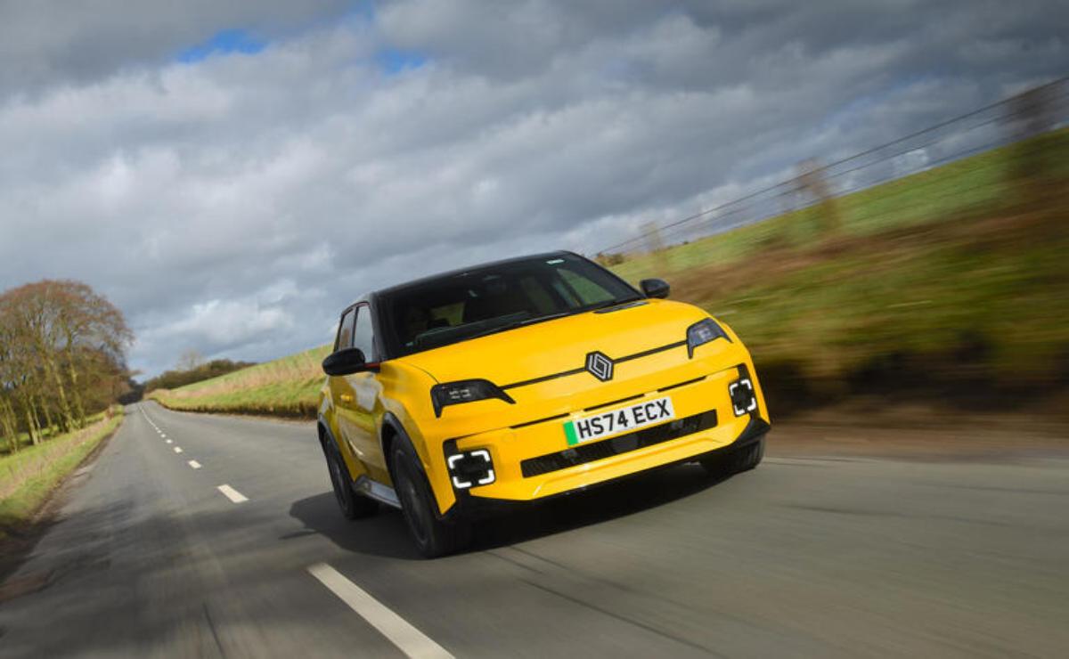 A yellow electric car driving on a countryside road under a cloudy sky.