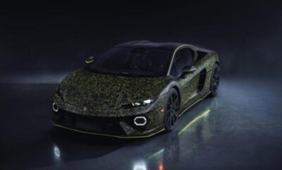 A sleek black sports car with a camo-patterned hood under dim lighting.
