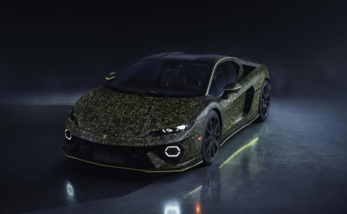 A sleek black sports car with a camo-patterned hood under dim lighting.