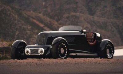 A sleek black vintage hot rod car parked on a desert road.