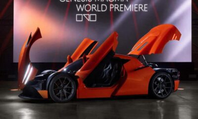 Sleek orange supercar with open butterfly doors at a world premiere event.