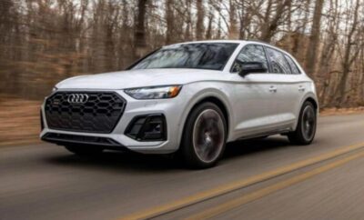 White Audi SUV driving on a forest road.