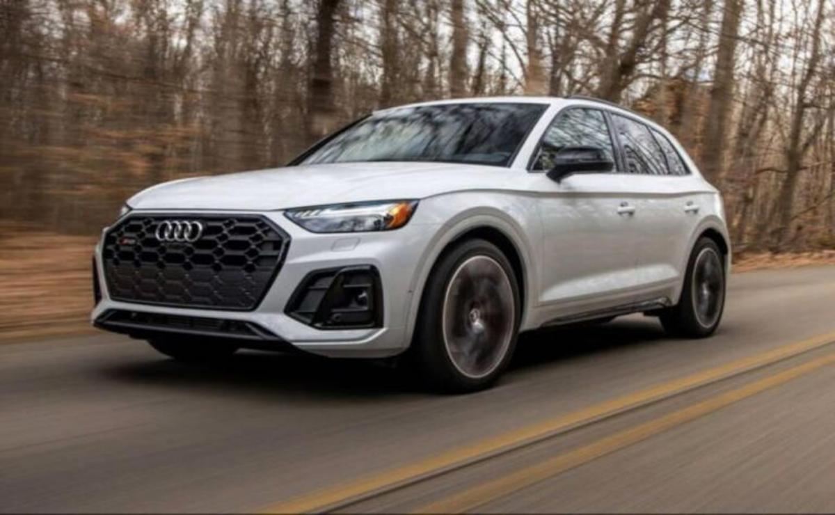 White Audi SUV driving on a forest road.