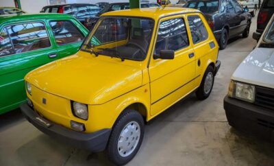 Bright yellow vintage compact car parked indoors.