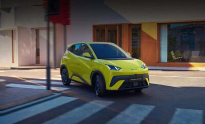 A vibrant yellow electric SUV driving on a city street.
