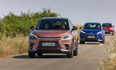 Two modern electric cars driving on a road in a natural setting.