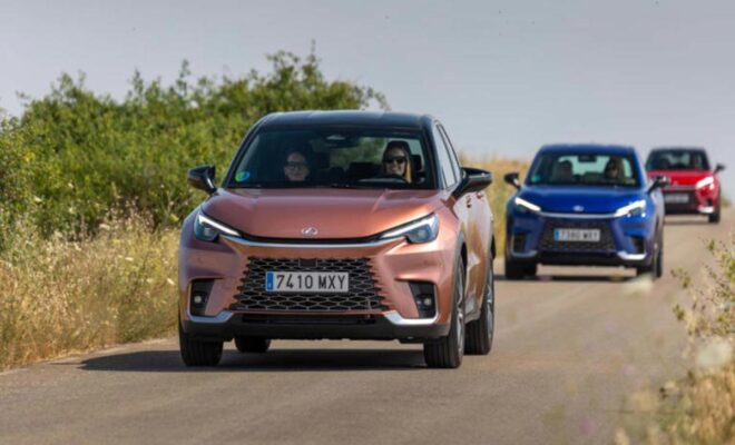 Two modern electric cars driving on a road in a natural setting.