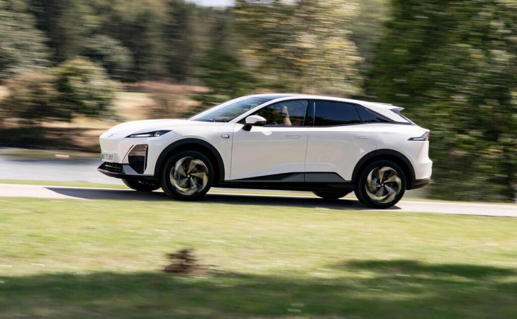 A man working on his laptop and writing in a notebook at a desk.