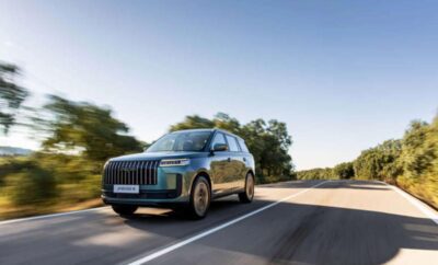 Luxury black SUV driving on a sunny road with clear skies.