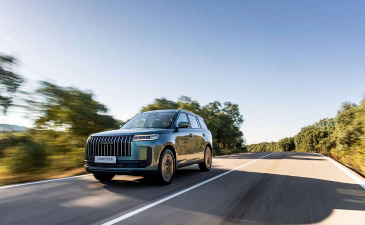 Luxury black SUV driving on a sunny road with clear skies.