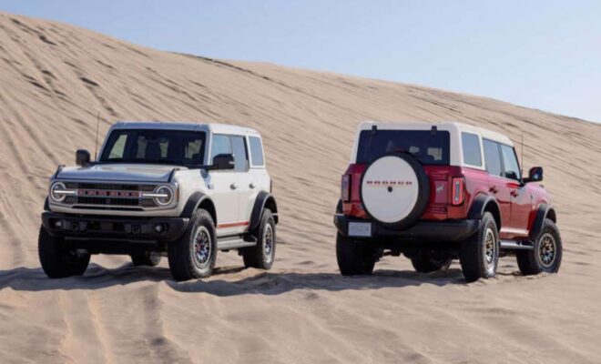 Two off-road SUVs parked on sandy desert dunes.