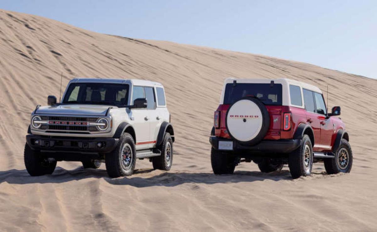 Two off-road SUVs parked on sandy desert dunes.