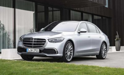 Silver Mercedes-Benz sedan parked in front of a modern building.
