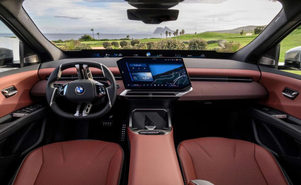 A man working on his laptop and writing in a notebook at a desk.