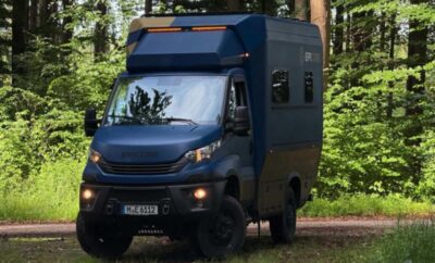 A rugged off-road camper van parked in a forest clearing.