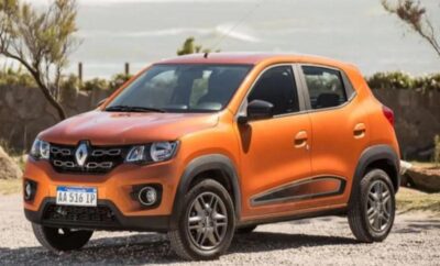 Orange compact SUV parked on a gravel road with greenery in the background.