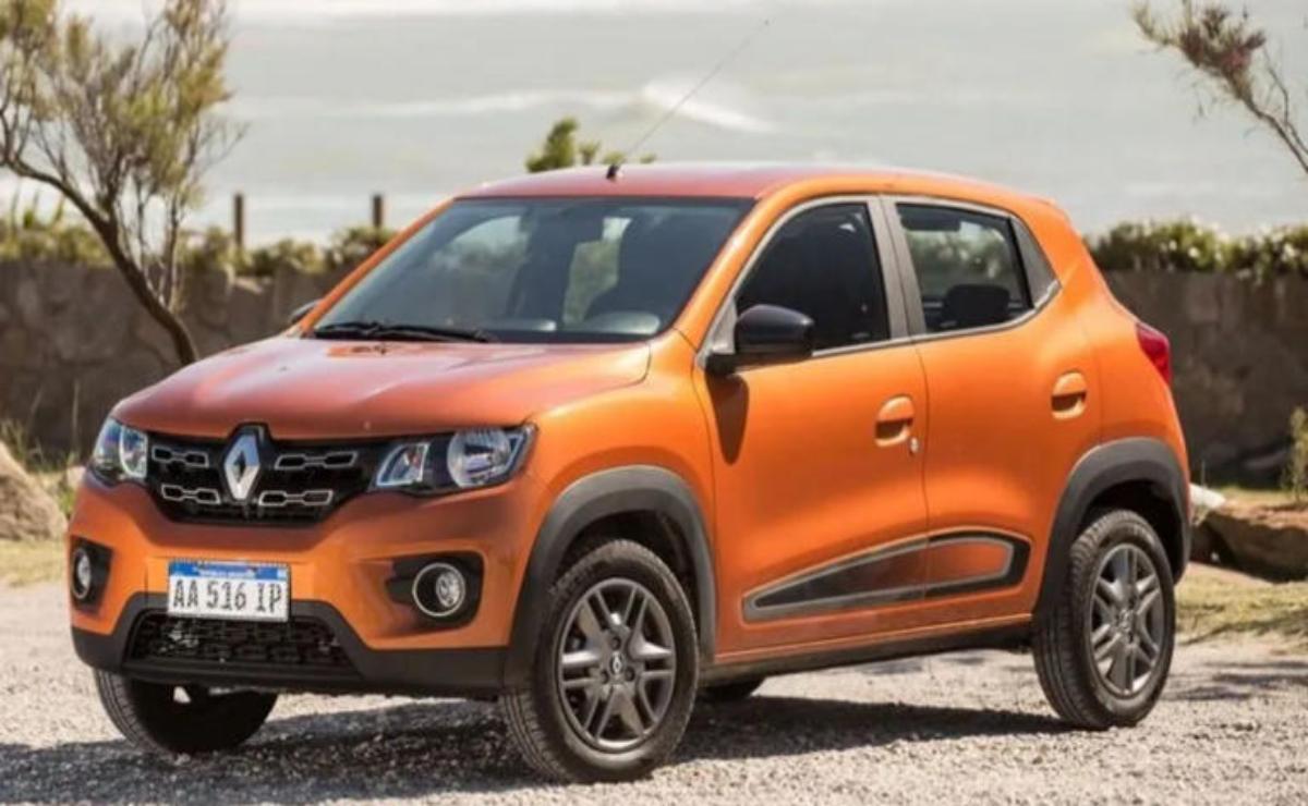 Orange compact SUV parked on a gravel road with greenery in the background.
