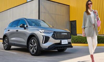 A modern silver SUV parked outside a yellow building.
