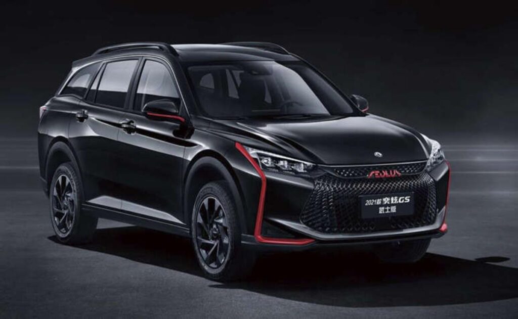 A man working on his laptop and writing in a notebook at a desk.