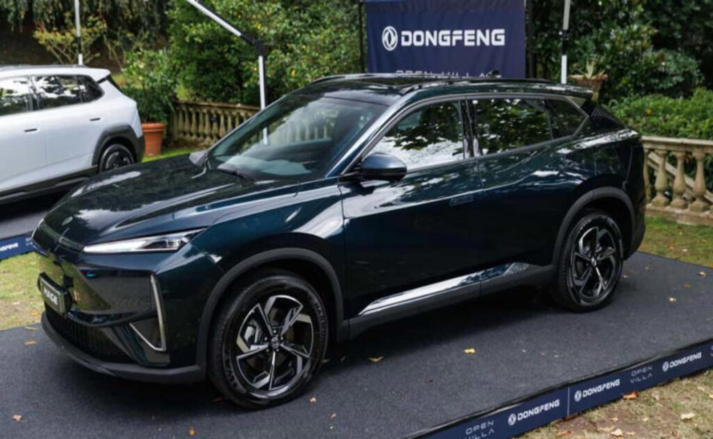 A man working on his laptop and writing in a notebook at a desk.