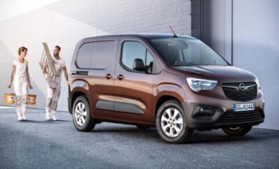 A brown modern cargo van parked near a building with a woman standing beside it.