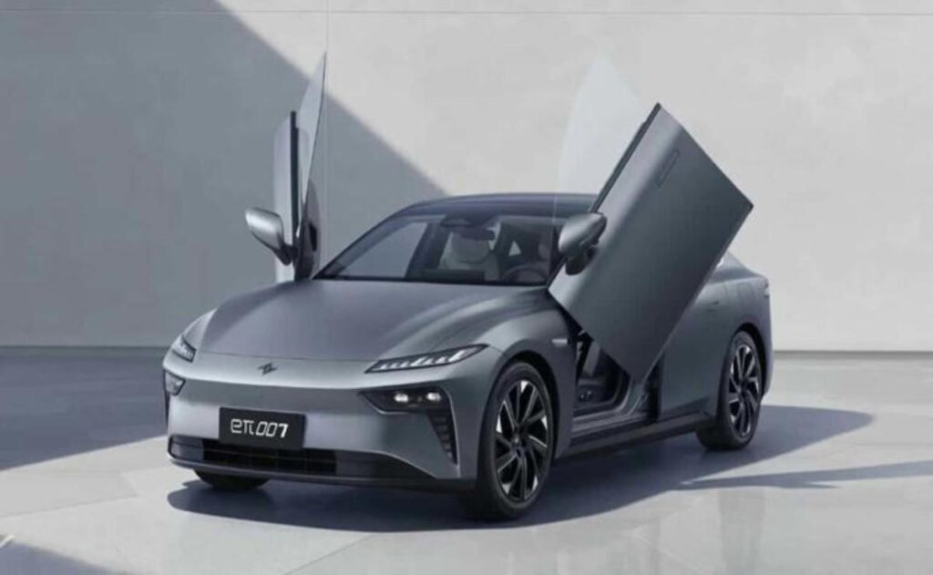 A man working on his laptop and writing in a notebook at a desk.