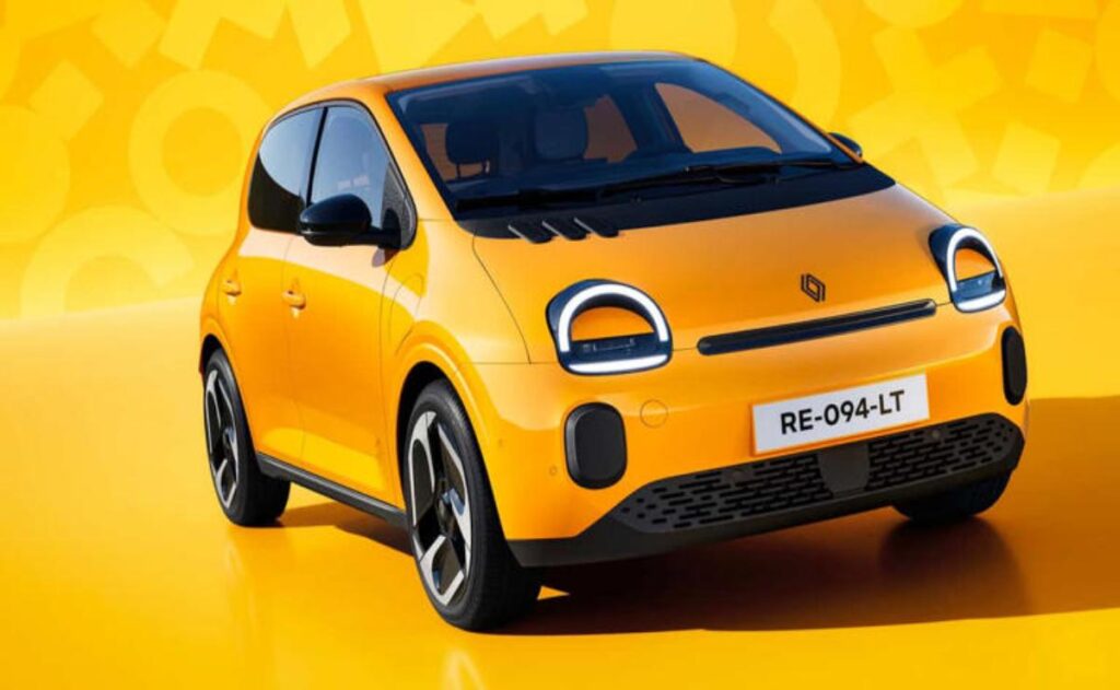 A man working on his laptop and writing in a notebook at a desk.