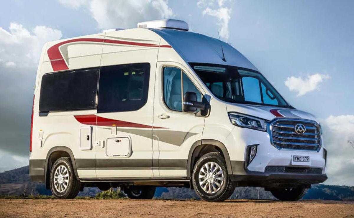 Modern camper van parked on a dirt road under a partly cloudy sky.