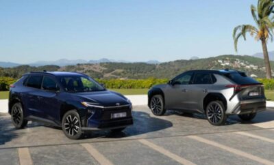 Two modern SUVs parked side by side in an open area with hills in the background.