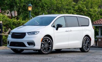A sleek white minivan parked near greenery with modern design features.