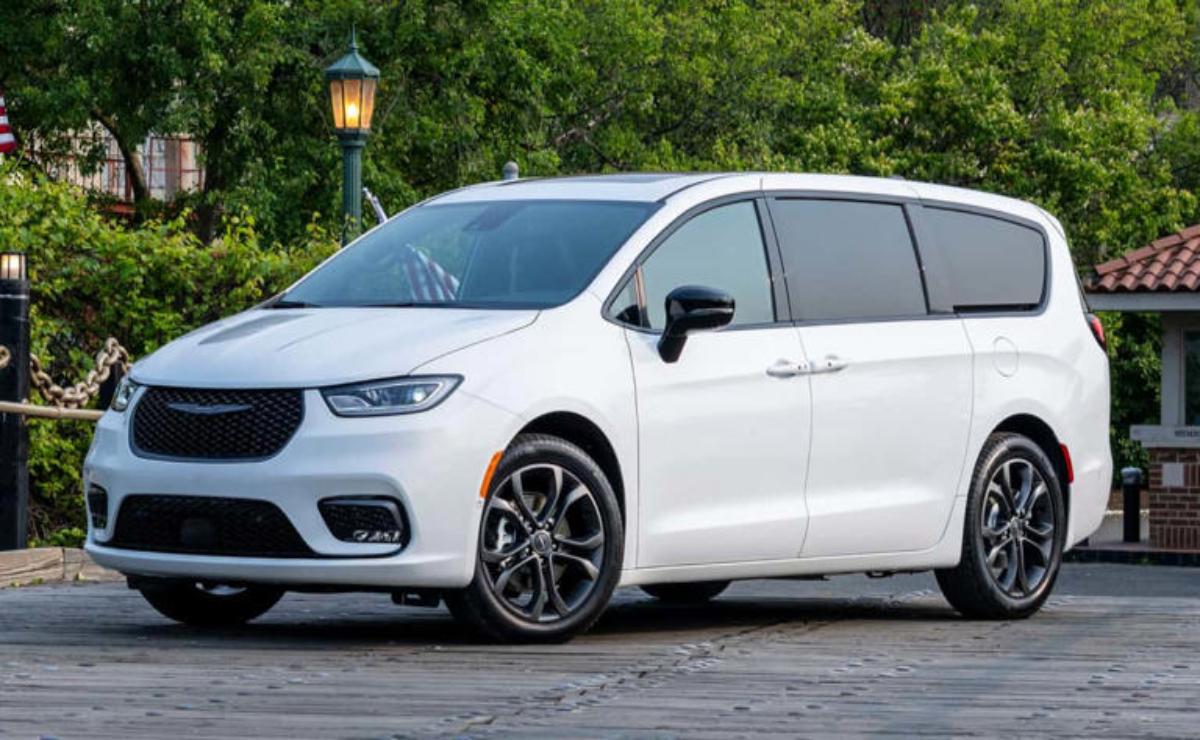 A sleek white minivan parked near greenery with modern design features.