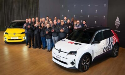 Group of people posing with a white electric car indoors.