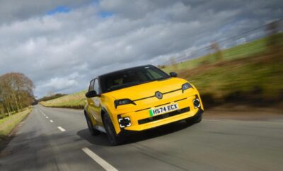 Yellow sporty car driving on a countryside road under a cloudy sky.