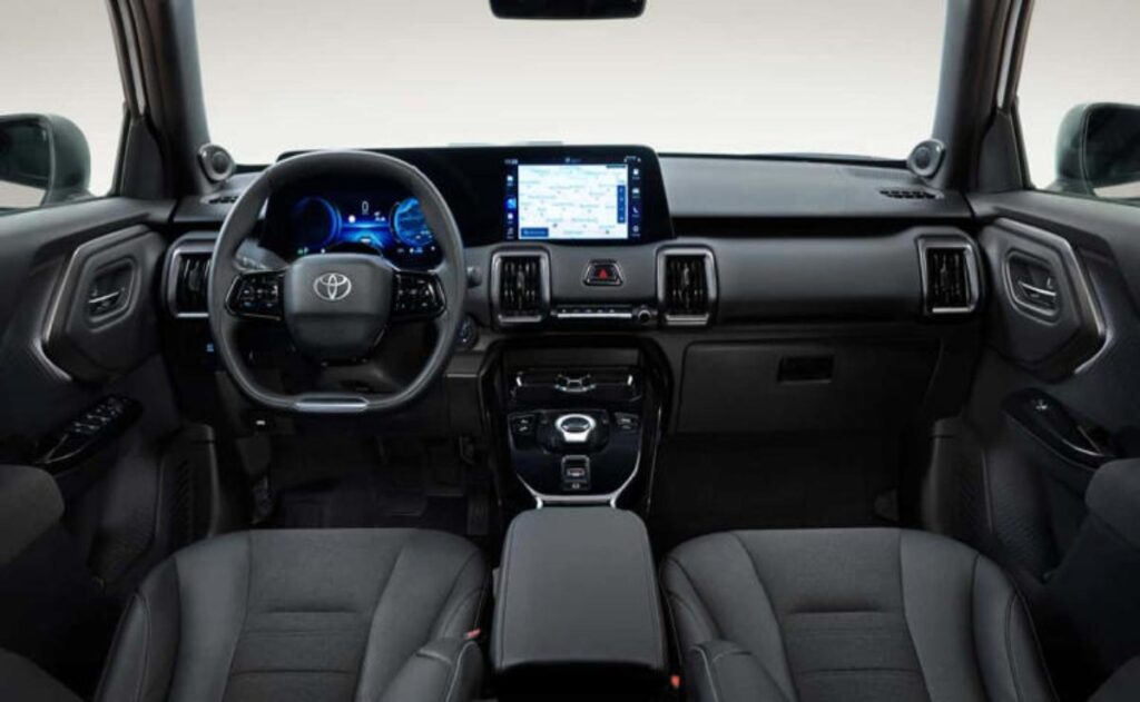 A man working on his laptop and writing in a notebook at a desk.