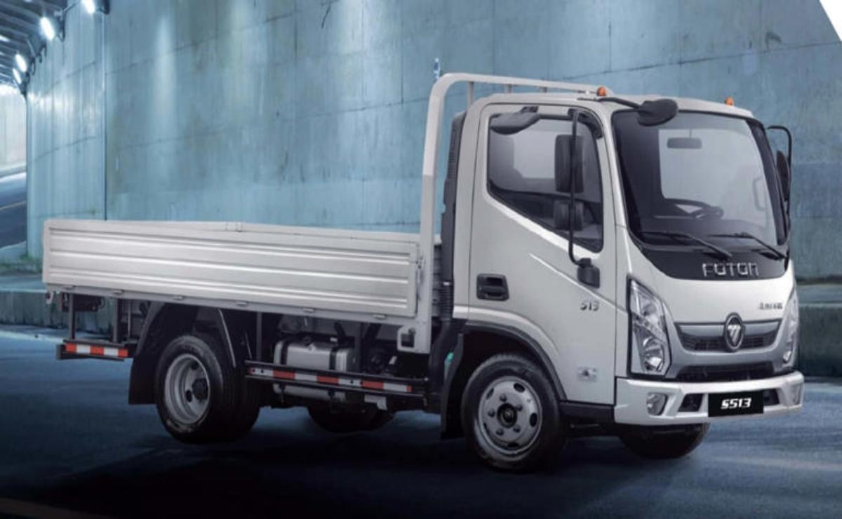 White flatbed truck parked against a blue textured wall.