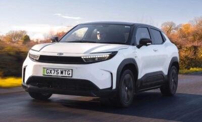 A sleek white electric SUV driving on the road during sunset.