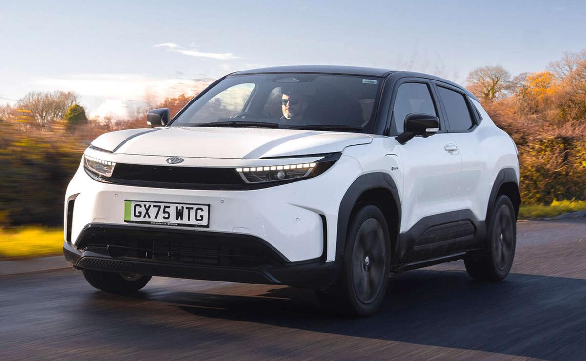 A sleek white electric SUV driving on the road during sunset.