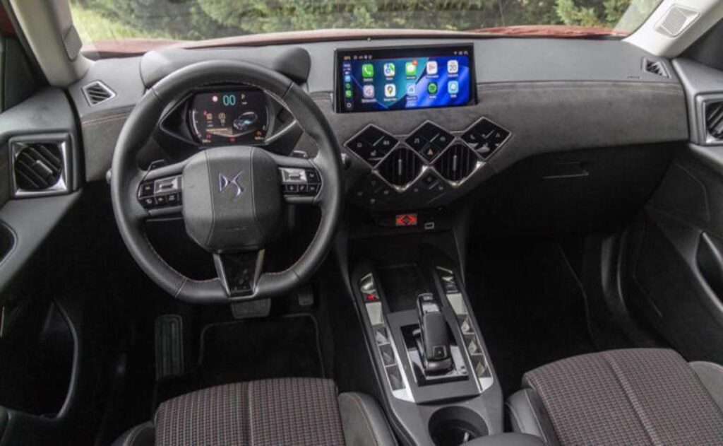 A man working on his laptop and writing in a notebook at a desk.