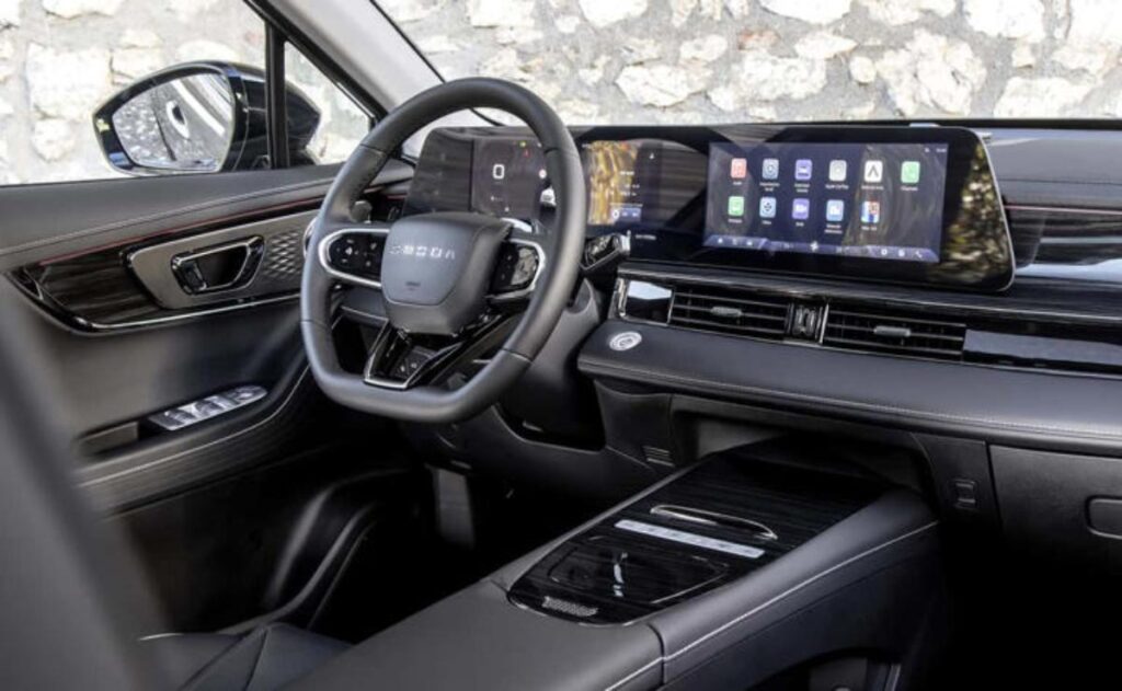 A man working on his laptop and writing in a notebook at a desk.