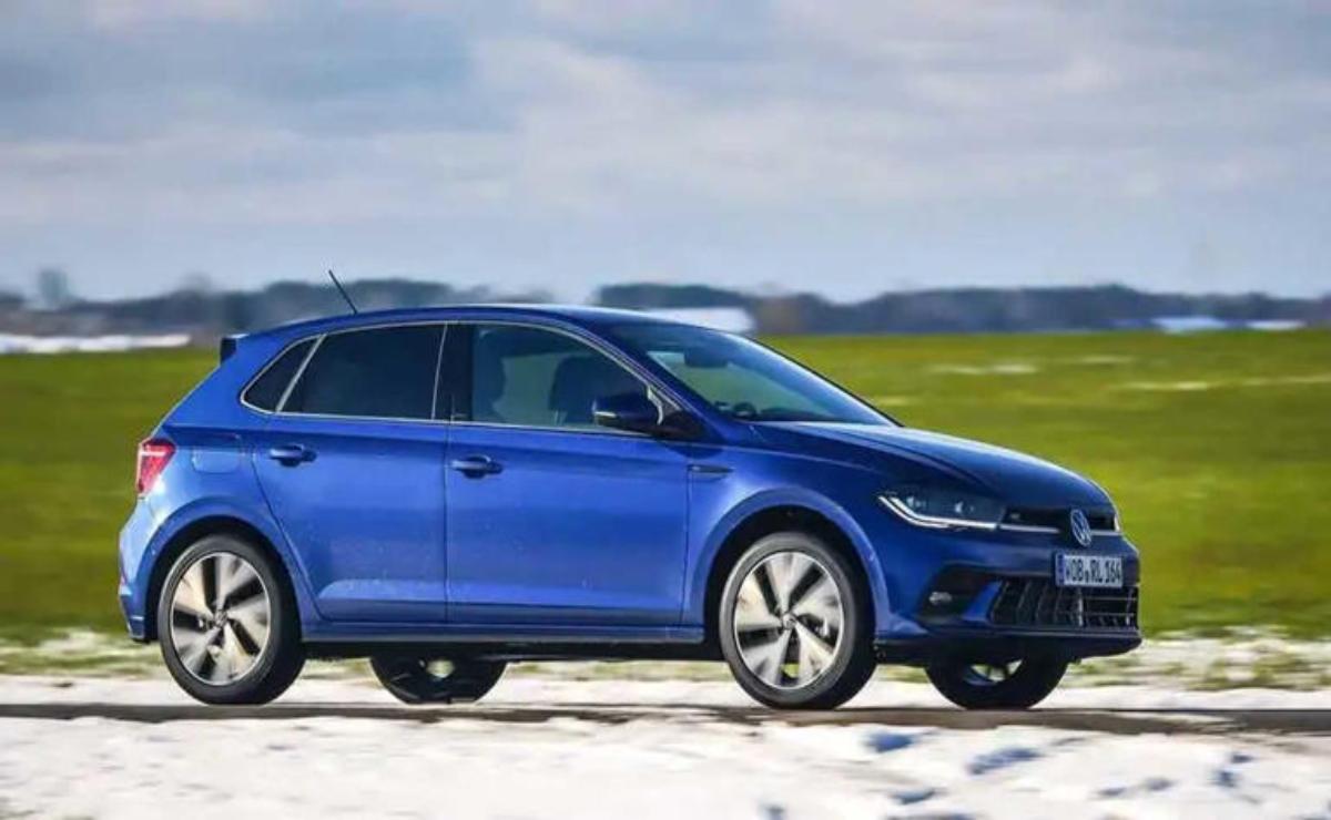 A sleek blue electric car parked on a snowy field with hills in the background.