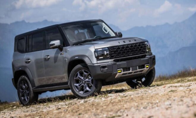 A rugged black SUV parked on rocky terrain under a cloudy sky.