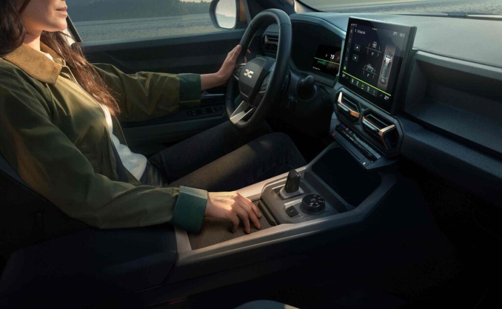 A man working on his laptop and writing in a notebook at a desk.