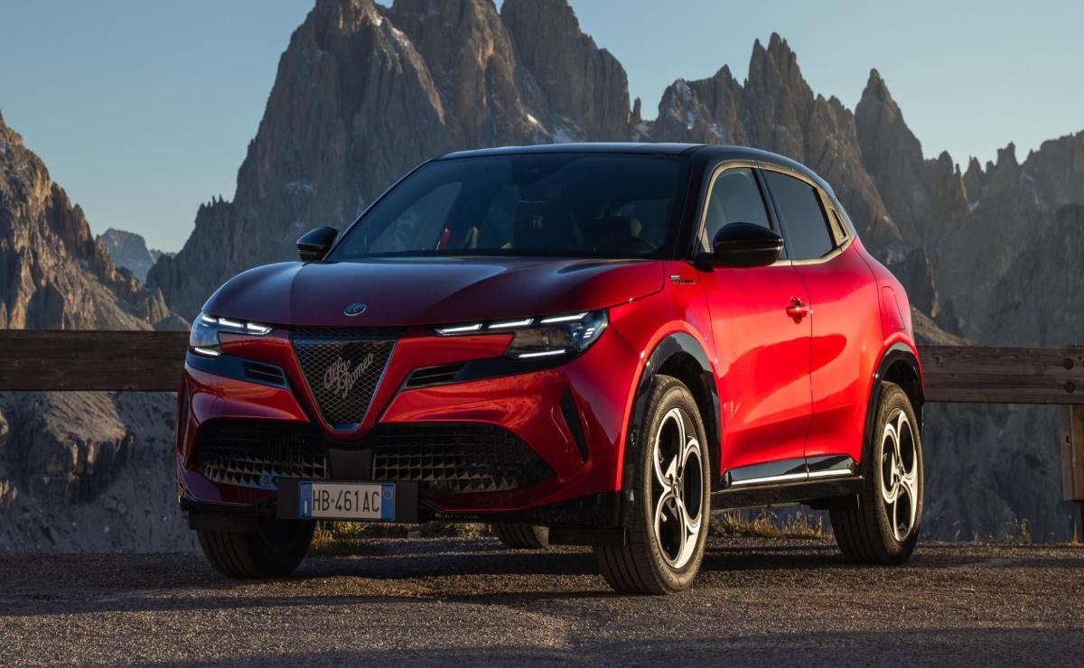 Sleek red SUV parked with mountains in the background at sunset.