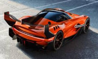 Sleek orange sports car parked on a road with dramatic lighting.