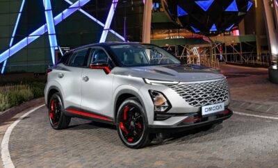 Sleek silver SUV with red accents parked at night under colorful lights.