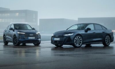 Two sleek black Audi electric cars parked side by side on a wet surface with a foggy background.